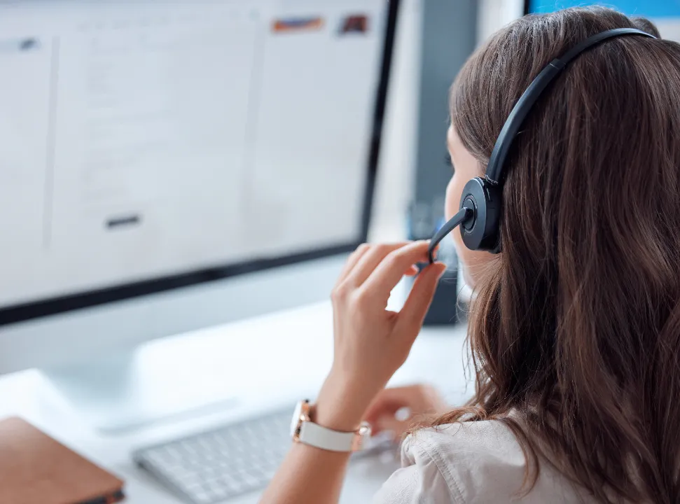Customer service adviser wearing a headset while working at a desktop computer.