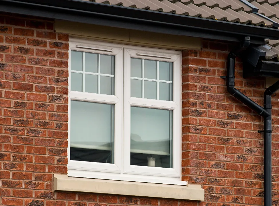 White uPVC double window with Georgian bars installed in a red-brick house.